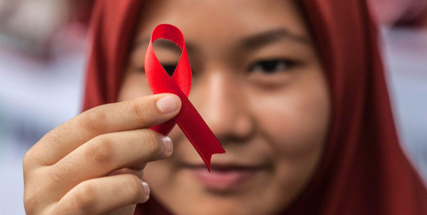Girl holding a red AIDS ribbon